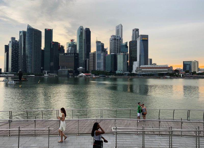 &copy; Reuters. Passers-by hold their mobile phones as people take a selfie photo using a smartphone, with Singapore&apos;s central business district skyline, in Singapore