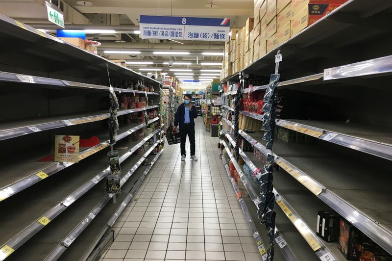 © Reuters. El cliente que lleva una máscara facial hace compras junto a estantes parcialmente vacíos de la sección de fideos instantáneos en un supermercado Carrefour, luego del brote de la nueva enfermedad por coronavirus (COVID-19), en Taipei, Taiwán