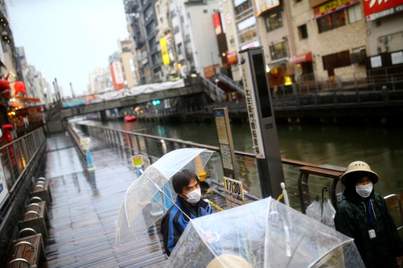&copy; Reuters. Workers, wearing protective masks following an outbreak of the coronavirus disease (COVID-19), receive tourists on an almost empty port in the Dotonbori entertainment district of Osaka