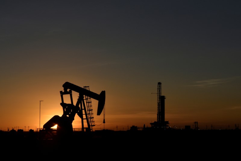 © Reuters. FILE PHOTO: A pump jack operates in front of a drilling rig at sunset in an oil field in Texas