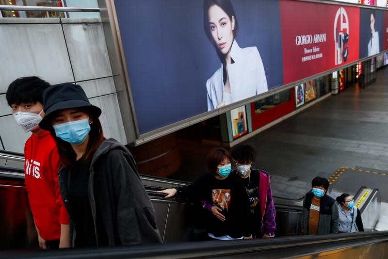 &copy; Reuters. Personas con máscaras protectoras caminan en un distrito comercial, después de un brote de la enfermedad coronavirus (COVID-19), en Pekín, China