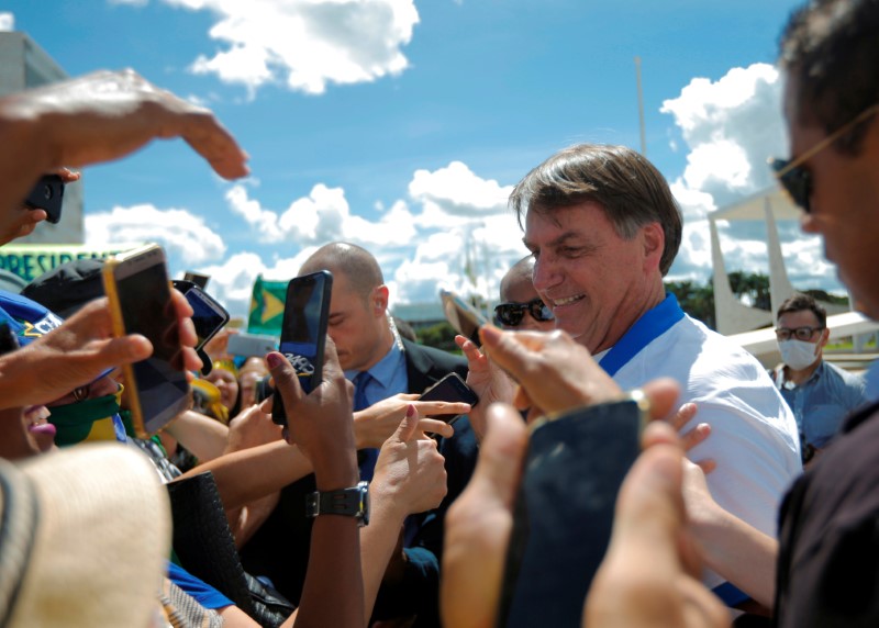 &copy; Reuters. Presidente Jair Bolsonaro cumprimenta apoiadores em frente ao Palácio do Planalto durante manifestação, já em meio à epidemia do coronavírus