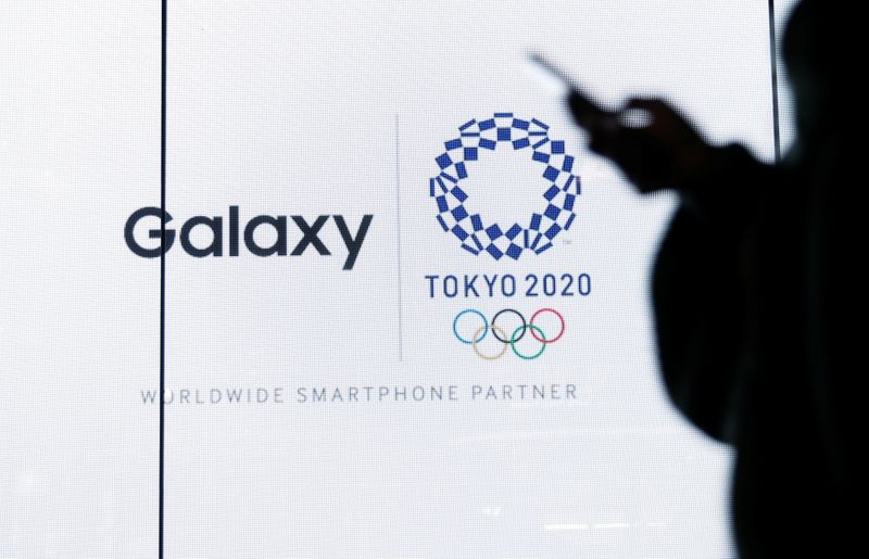 &copy; Reuters. A woman uses her smartphone as an electric screen displaying logos of Tokyo 2020 Olympic Games and Galaxy at Galaxy Harajuku in Tokyo