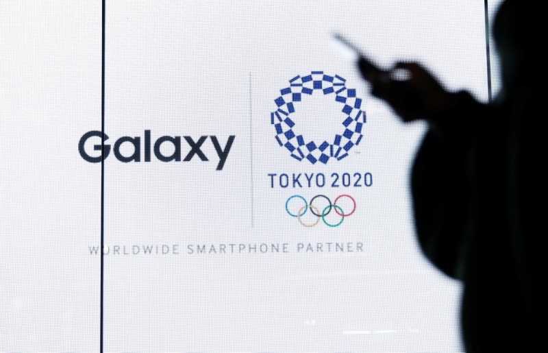 &copy; Reuters. A woman uses her smartphone as an electric screen displaying logos of Tokyo 2020 Olympic Games and Galaxy at Galaxy Harajuku in Tokyo