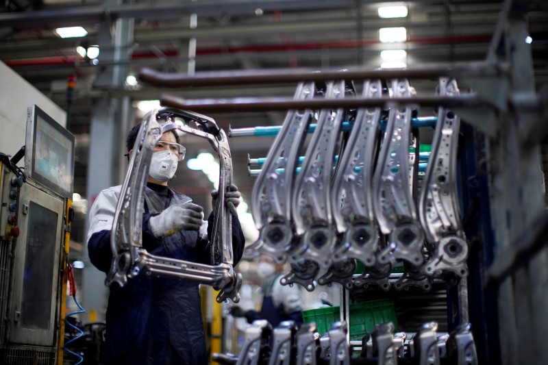 © Reuters. Employee wearing a face mask works on a car seat assembly line at Yanfeng Adient factory in Shanghai