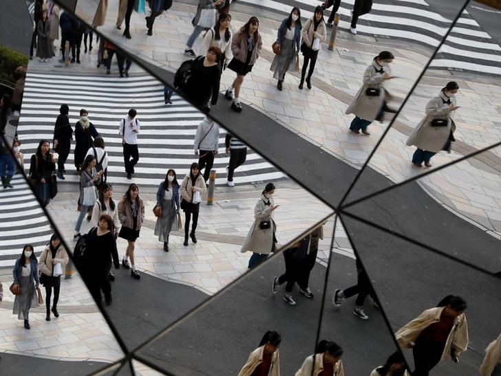 &copy; Reuters. Riflesso di alcuni passanti con addosso mascherine protettive all&apos;interno di un centro commerciale a Tokyo, 26 marzo 2020