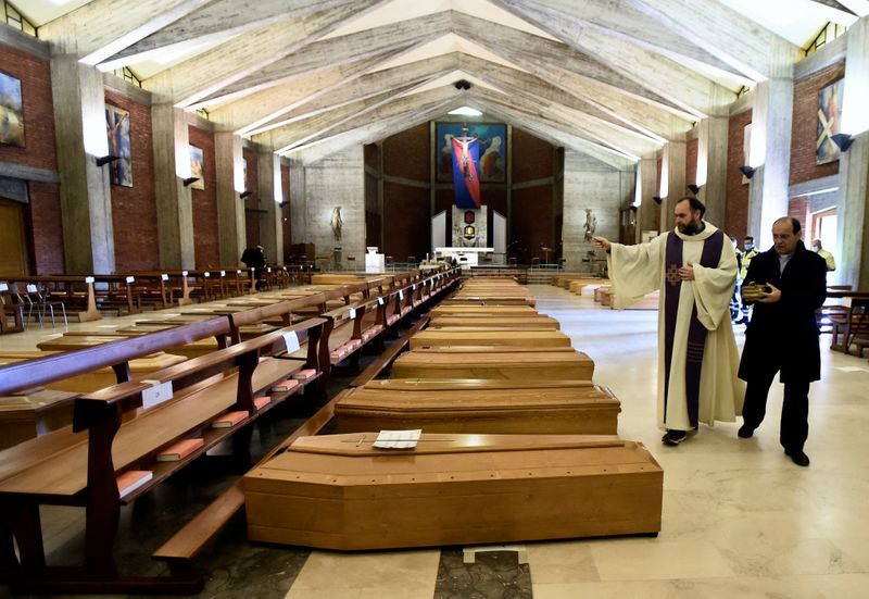 &copy; Reuters. Un sacerdote local bendice los ataúdes almacenados en una iglesia en Seriate
