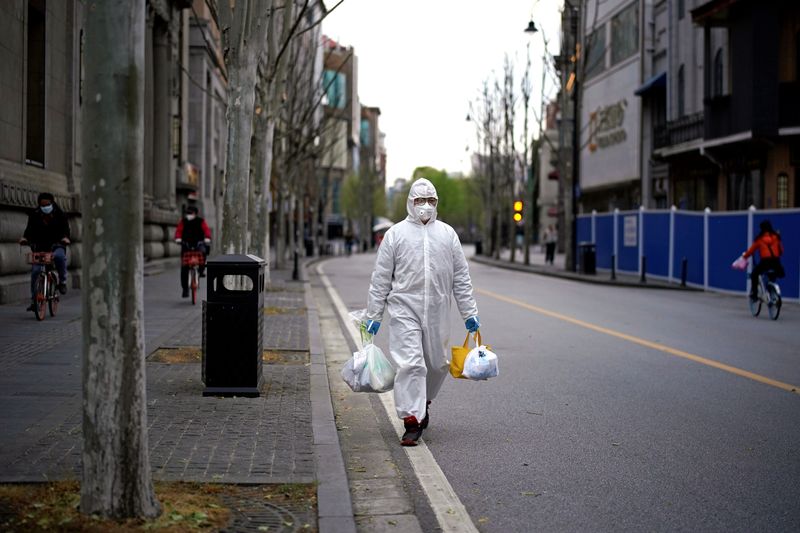 © Reuters. Man wearing a hazmat suit walks on a street in Wuhan