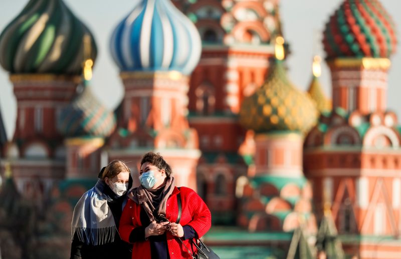 &copy; Reuters. FILE PHOTO: Women with protective masks walk across Red Square in Moscow