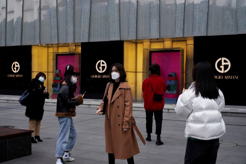 © Reuters. People wearing face masks are seen outside a Giorgio Armani store at a shopping mall in Wuhan