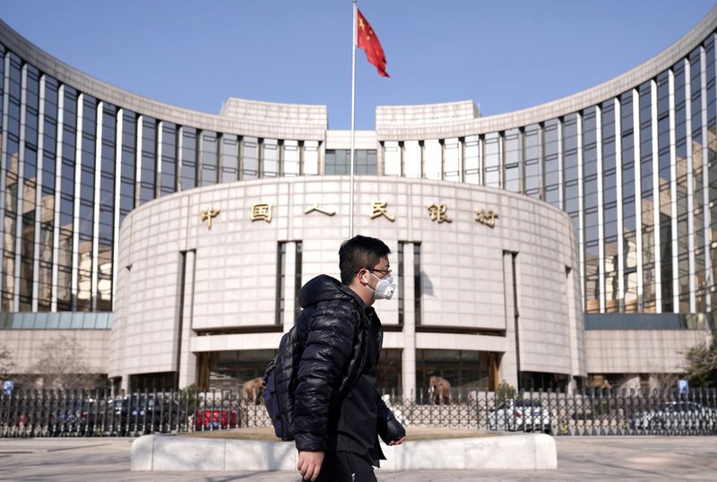 © Reuters. Man wearing a mask walks past the headquarters of the People's Bank of China, the central bank, in Beijing