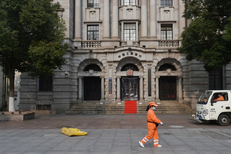 &copy; Reuters. Sanitation worker wearing a face mask walks past a branch of ICBC in Wuhan