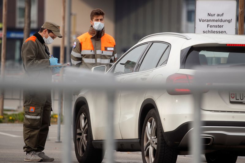 &copy; Reuters. Civil defence workers check papers of driver before he can enter a drive-in test center in Luzern