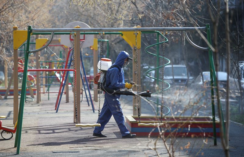 &copy; Reuters. Специалист в защитном костюме дезинфицирует детскую площадку в Алма-Ате