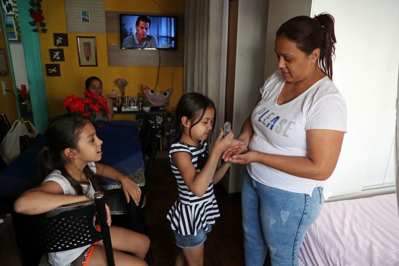 © Reuters. Jovem garota aplica álcool gel em sua mãe em São Paulo (SP) durante pandemia de coronavírus