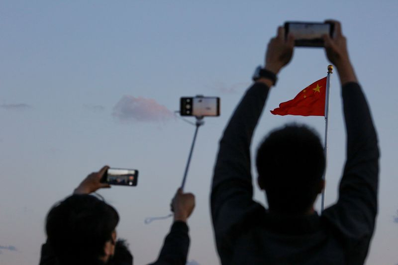 &copy; Reuters. FILE PHOTO: People take pictures of the lowering ceremony of the Chinese national flag that is held daily at sunset in Tiananmen Square in Beijing