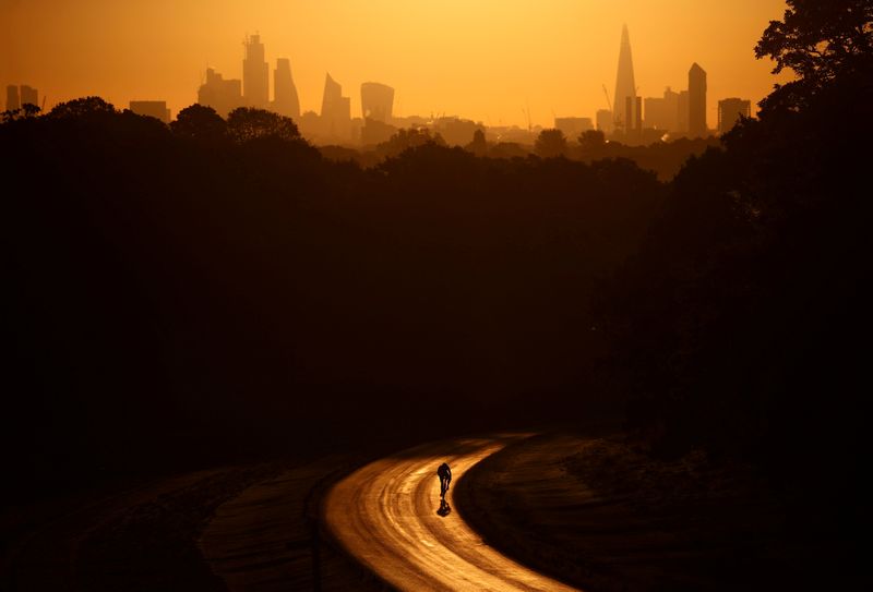 &copy; Reuters. FILE PHOTO: The sun rises behind The Shard and the financial district as a cyclist rides through Richmond Park in London