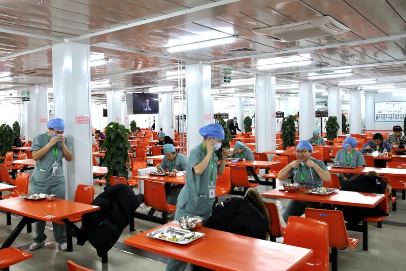 © Reuters. Medical workers eat at separate tables at a canteen inside Xiaotangshan Hospital in Beijing