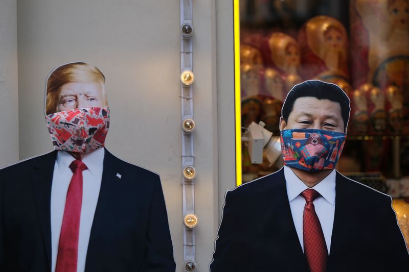 &copy; Reuters. Картонные фигуры президента США Дональа Трампа и председателя КНР Си Цзиньпина в защитных масках у сувенирного магазина в Москве