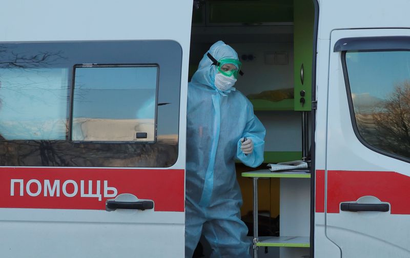 &copy; Reuters. Медработник в защитном костюме в машине скорой помощи у общежития в Минске