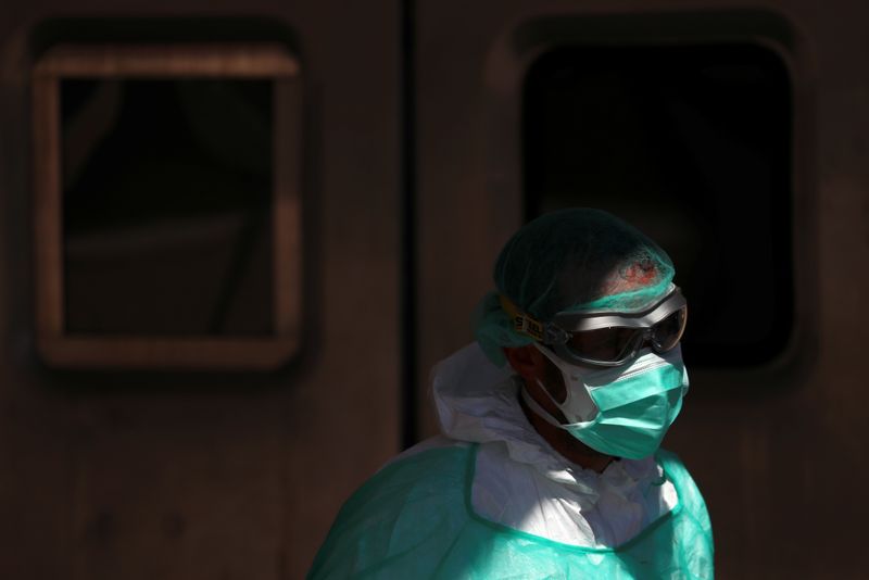 &copy; Reuters. Agente da saúde com roupa de proteção caminha próximo à entrada de unidade emergencial em Madri