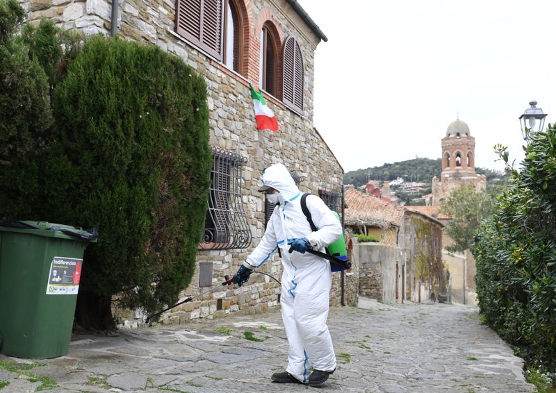 &copy; Reuters. Un trabajador rocía desinfectante sobre los edificios del centro medieval de Castiglione della Pescaia en Grosseto