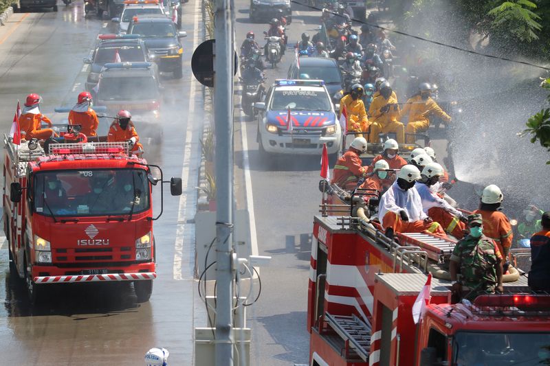 © Reuters. Officers spray disinfectant on a road to prevent the spread of coronavirus disease (COVID-19) in Surabaya