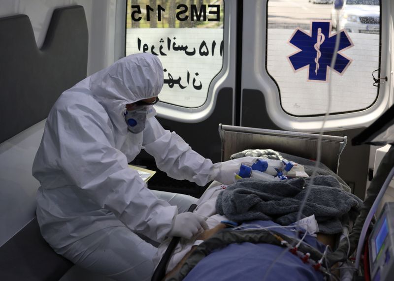 &copy; Reuters. Membro de equipe de emergência médica com traje de proteção trata de paciente em Teerã