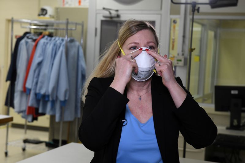 &copy; Reuters. FILE PHOTO: Dr. Nicole McCullough, a global health and safety expert at 3M, demonstrates the correct way to put on a N95 respiratory mask at a laboratory of 3M in Maplewood, Minnesota
