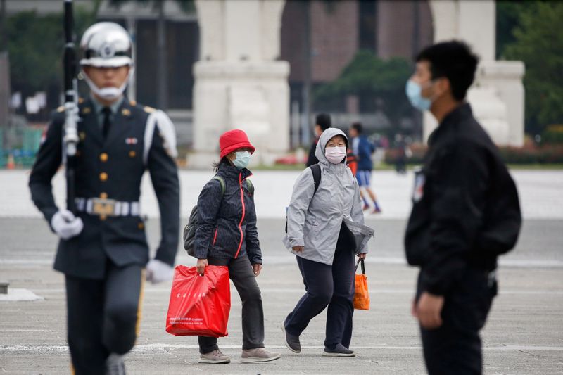 &copy; Reuters. FILE PHOTO: Tourists wear protective face masks to protect themselves from coronavirus disease (COVID-19) while passing by a flag rising ceremony at Chiang Kai Shek Memorial Hall in Taipei