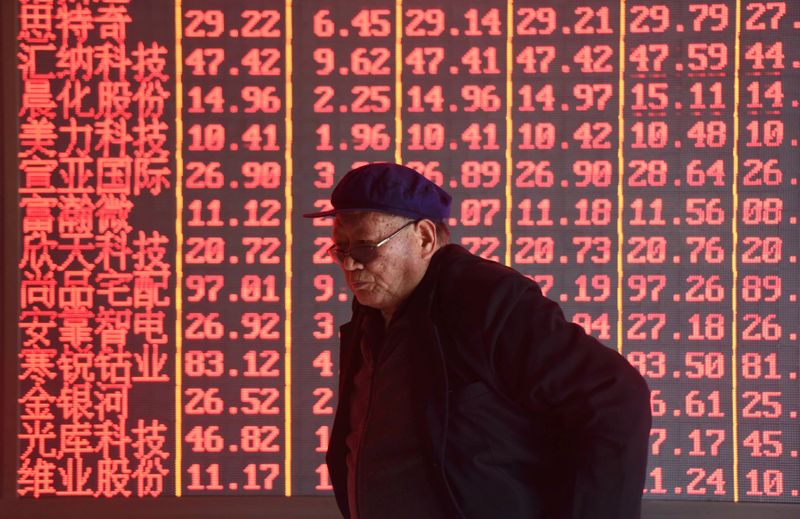 &copy; Reuters. Man stands in front of an electronic board displaying stock information at a brokerage firm in Hangzhou