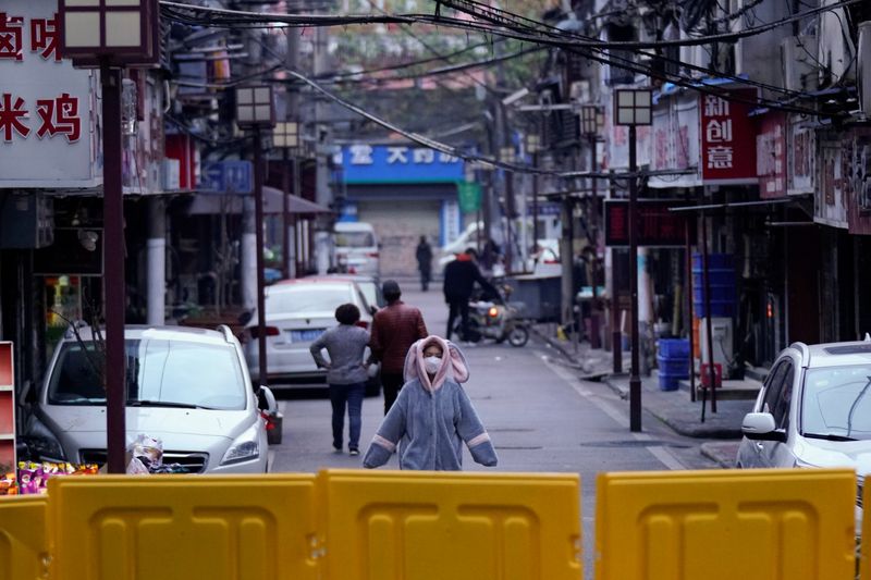 © Reuters. Mulher com máscara de proteção em área residencial bloqueada em Wuhan