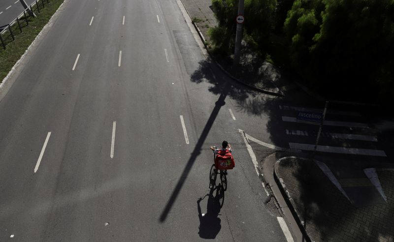 © Reuters. Entregador do iFood passa de bicicleta por avenidas vazias de  São Paulo em meio à pandemia de coronavírus