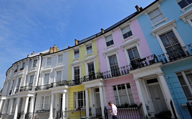&copy; Reuters. A man walks past houses painted in various colours in a residential street in London