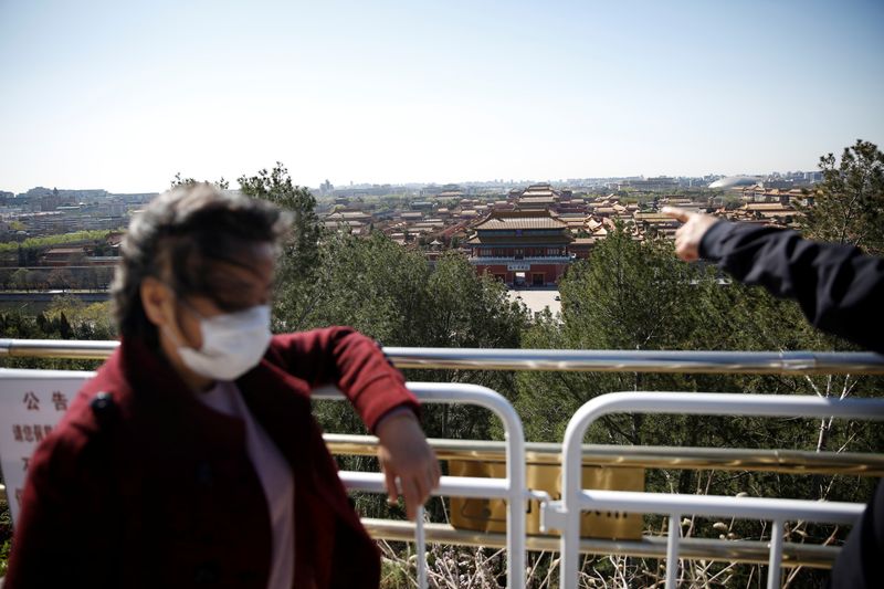 © Reuters. Visitors wearing face masks are seen at a peak overlooking the Forbidden City at Jingshan Park, amid the novel coronavirus disease (COVID-19) outbreak in the country, in Beijing