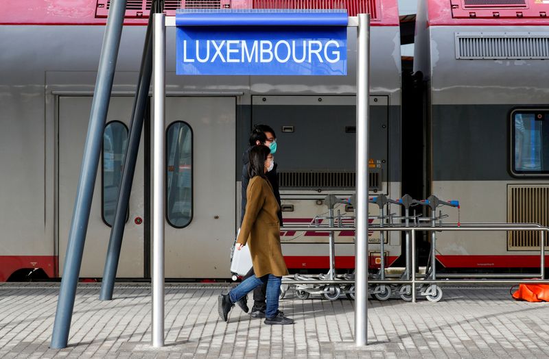 © Reuters. FILE PHOTO: Tourists wearing masks walk on a platform at Luxembourg railway station