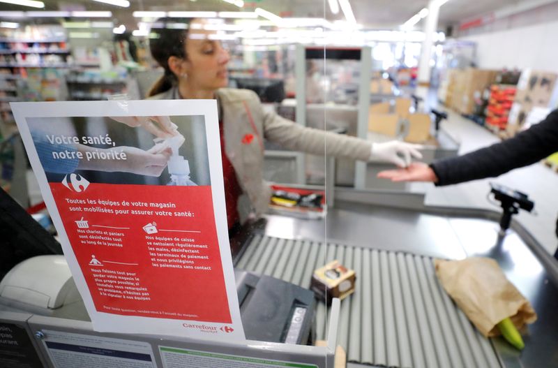 &copy; Reuters. A cashier serves a customer behind a plastic protection shield at a supermarket in Coueron near Nantes