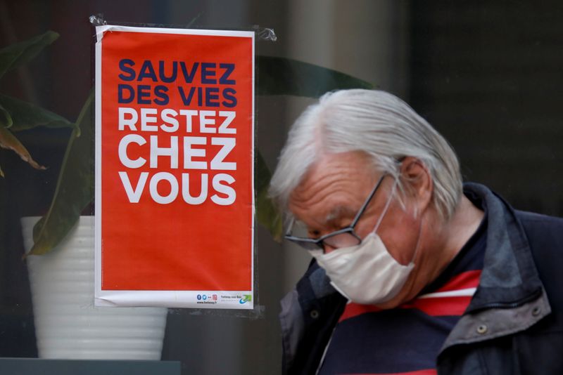 &copy; Reuters. Homem com máscara de proteção passa por placa &quot;Salve vidas, fique em casa&quot; na França