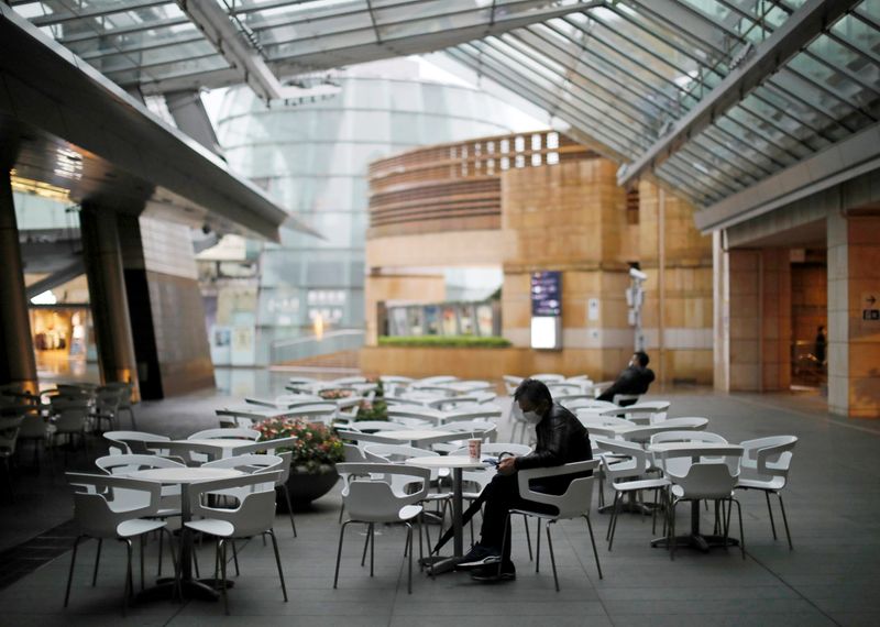 &copy; Reuters. People wearing protective face masks, following an outbreak of the coronavirus disease (COVID-19), takes a rest next to almost empty seats of a cafe and restaurant at the Roppongi Hills complex in Tokyo