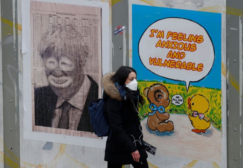 &copy; Reuters. Una mujer con mascarilla pasa junto a un póster ridiculizando al primer ministro británico, Boris Johnson, en Manchester, Reino Unido.
