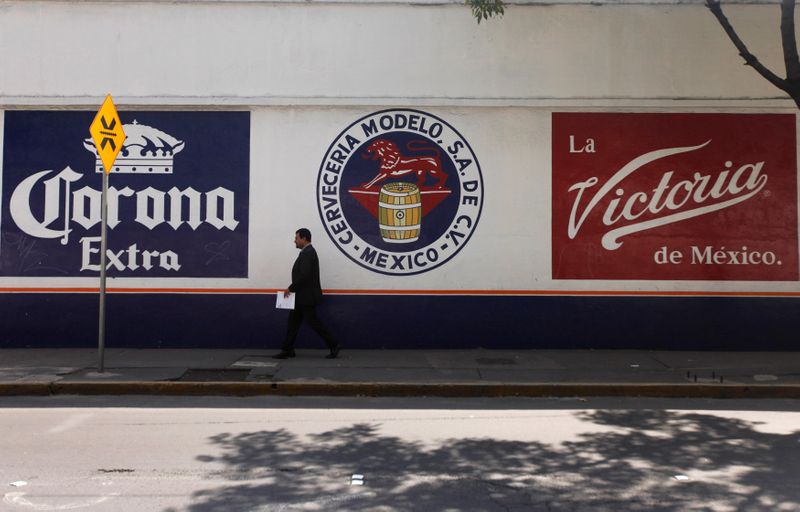 © Reuters. Imagen de archivo. Un hombre camina junto al logotipo de Grupo Modelo en Ciudad de México.