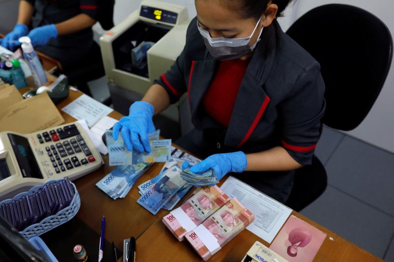 &copy; Reuters. An employee wearing a face mask and synthetic gloves counts Indonesia&apos;s rupiah banknotes at a currency exchange office amid the spread of coronavirus disease (COVID-19) in Jakarta