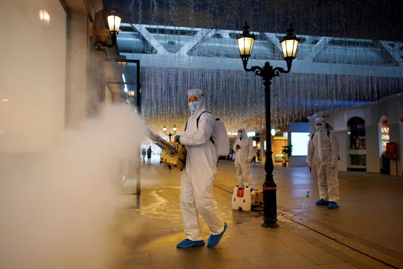 &copy; Reuters. Voluntarios con trajes protectores desinfectan un complejo comercial en Wuhan