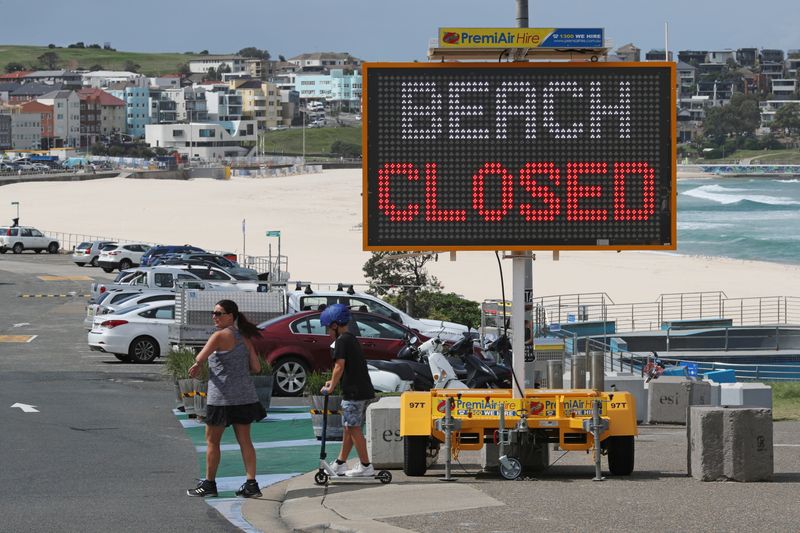 &copy; Reuters. FOTO DE ARCHIVO: Dos personas cruzan ante una señal en la que se lee &quot;Playa cerrada&quot; en Bondi Beach