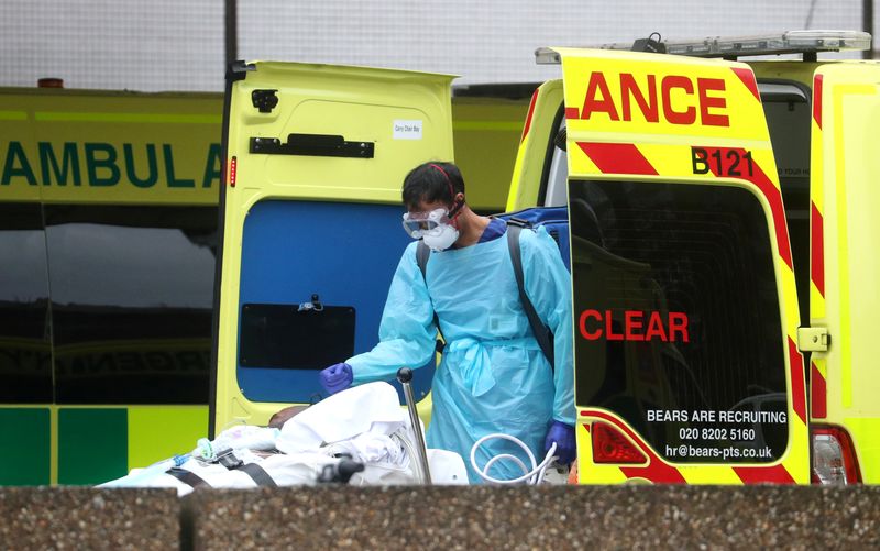 &copy; Reuters. Paramédico com máscara e luvas de proteção contra coronavírus conduz paciente a hospital em Londres
