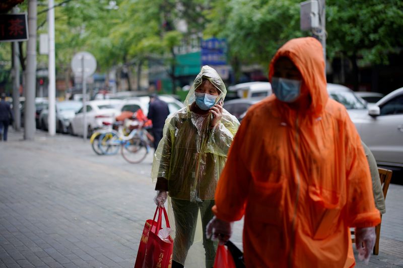 &copy; Reuters. Pessoas com máscaras de proteção caminham em rua de Wuhan
