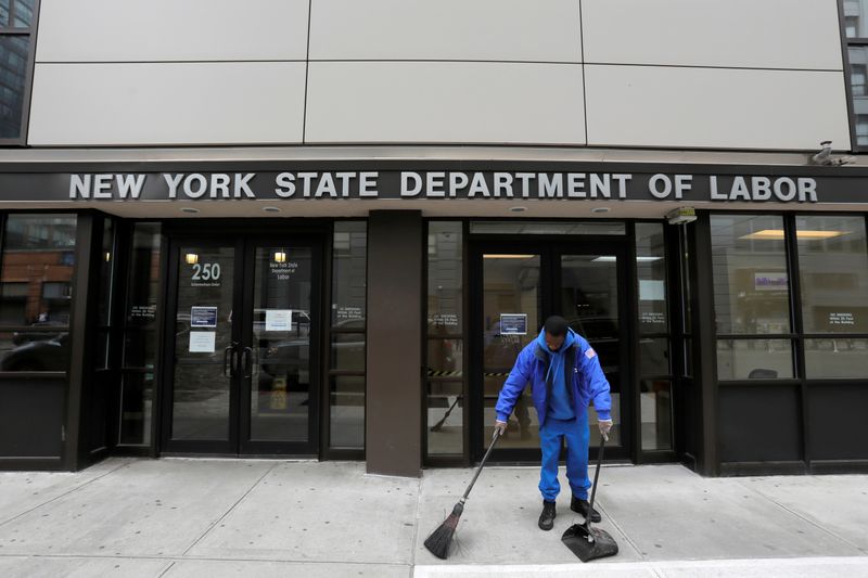 &copy; Reuters. Una persona spazza davanti l&apos;entrata del Dipartimento del Lavoro dello Stato di New York