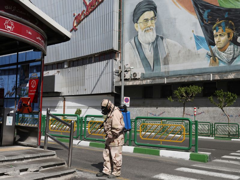 &copy; Reuters. Voluntário com trajes de proteção desinfeta ponto de ônibus em Teerã