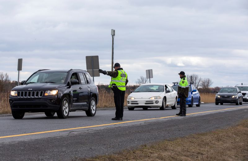 &copy; Reuters. Surete du Quebec police officers set up a checkpoint for drivers approaching the province from neighbouring Ontario