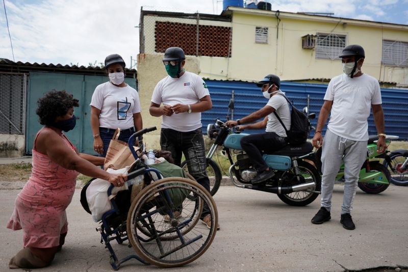 © Reuters. Bikers deliver donated food to a woman with disability amid concerns about the spread of coronavirus disease (COVID-19), in Havana